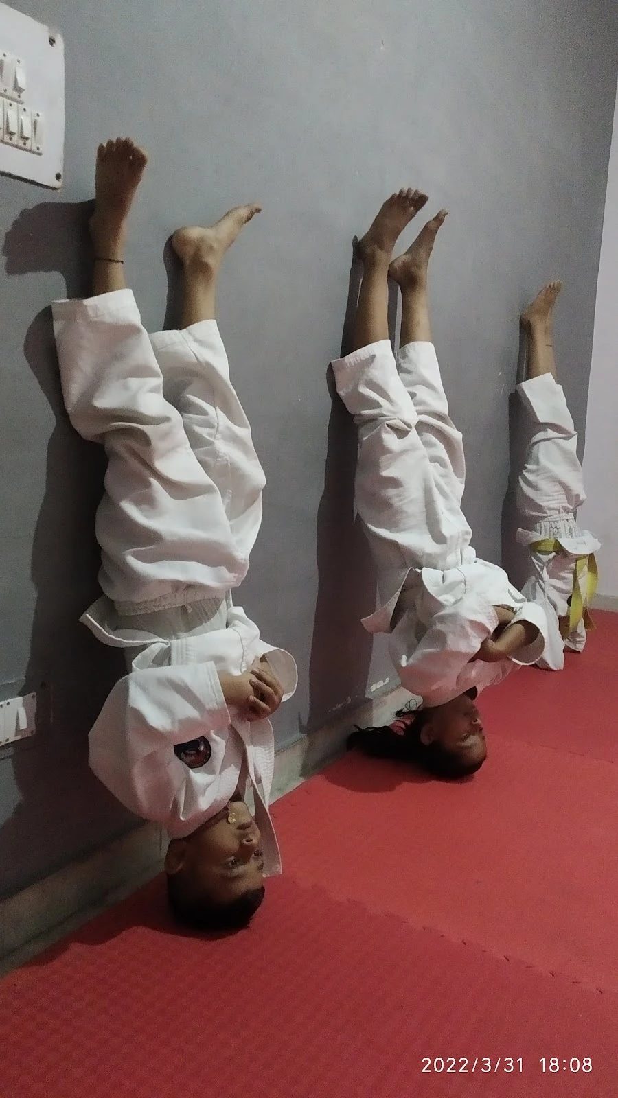 Young students practising supported balance against the academy wall